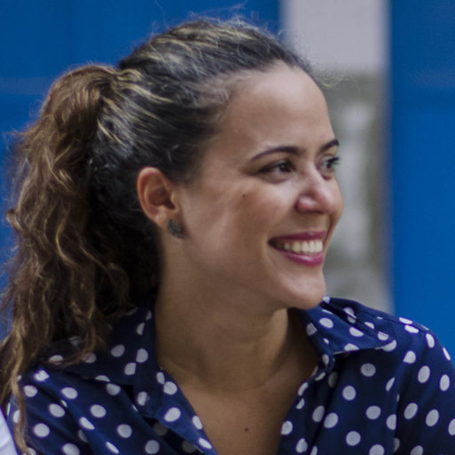 Mulher sorridente, cabelo prezo, vestida com bluza azul