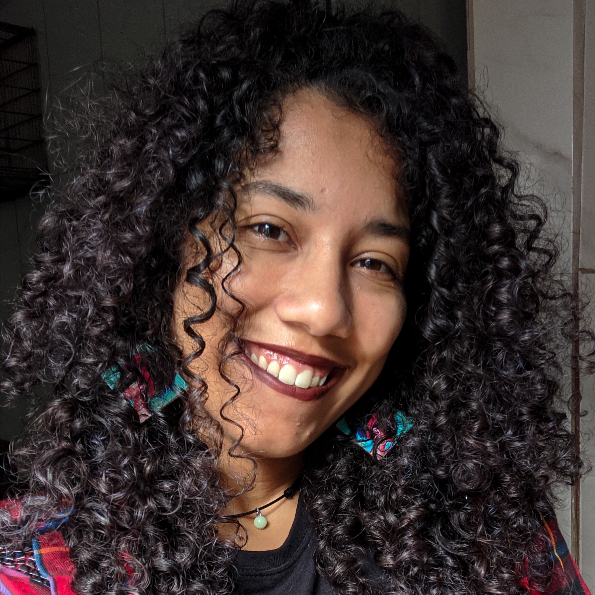 Mulher negra sorridente com cabelo cacheado